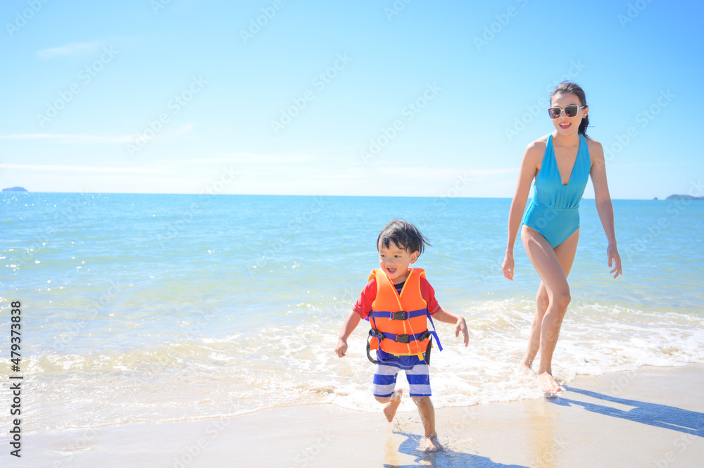 Mother and baby boy waer life vest at the beach