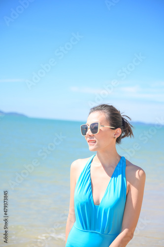 Woman enjoying beach relaxing joyful in summer by tropical blue water. model on travel wearing sun glasses. © grooveriderz