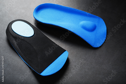 Orthopedic insoles for correction of the blue color of the foot on a black background.