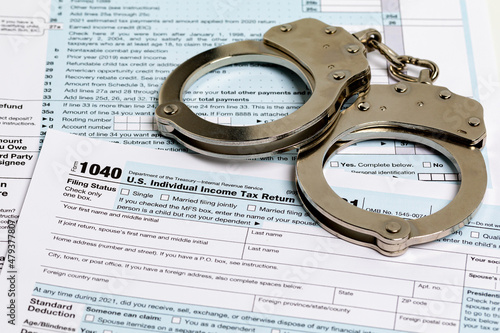 Income tax return documents and handcuffs. Tax evasion, crime and fraud concept. photo