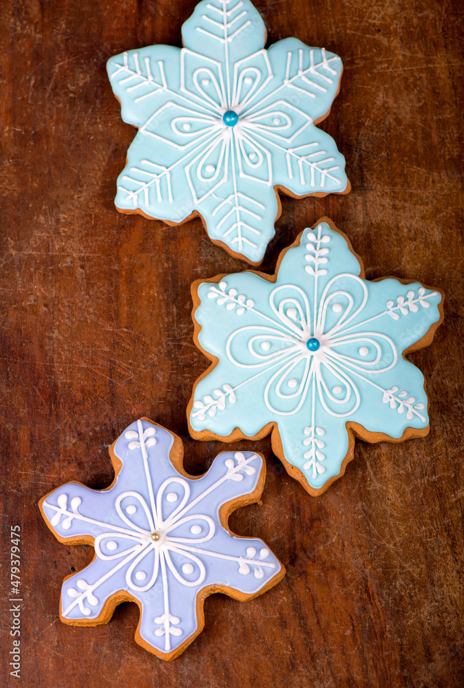 Homemade gingerbread cookies, festive Christmas and New Year sweets in the form of blue snowflakes background card, on a wooden board Homemade gingerbread cookies, festive Christmas and New Year sweets in the form of blue snowflakes background card, on a wooden board