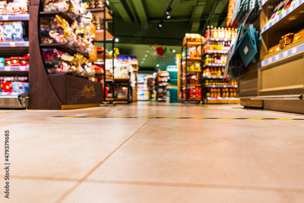 Grocery store. In the mall. Go shopping. Shelves with various goods. Product selection. Daily worries. The era of consumption. Focus on the floor. Close-up view from the level of the floor tiles.