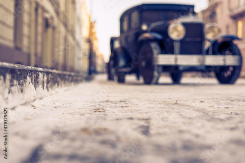 Winter in the city. The car is parked at the sidewalk. Antique car. Historical center of the city. Frosty snowy day. Focus on the road. Close up view from the level of the road.