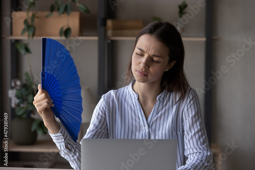 Obraz na plátne Exhausted office employee suffering from heat, hot stuffy air, working at laptop from home without conditioner on summer day