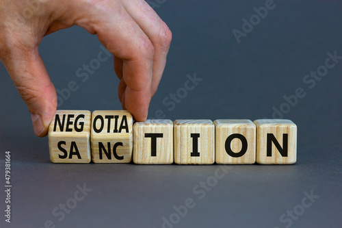 Sanction or negotiation symbol. Businessman turns cubes, changes the word sanction to negotiation. Beautiful grey table, grey background, copy space. Business, sanction or negotiation concept.