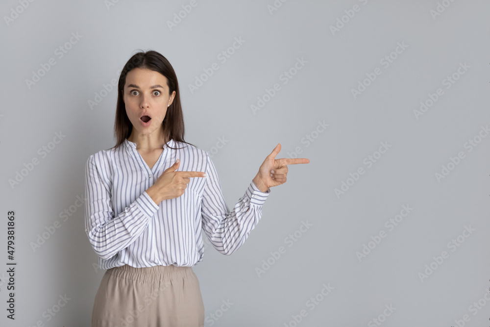 Shocked excited surprised young woman advertising sale, discount, promo. Female customer, client, consumer looking at camera, pointing at copy space. Head shot portrait isolated on white background Shocked excited surprised young woman advertising sale, discount, promo. Female customer, client, consumer looking at camera, pointing at copy space. Head shot portrait isolated on white background