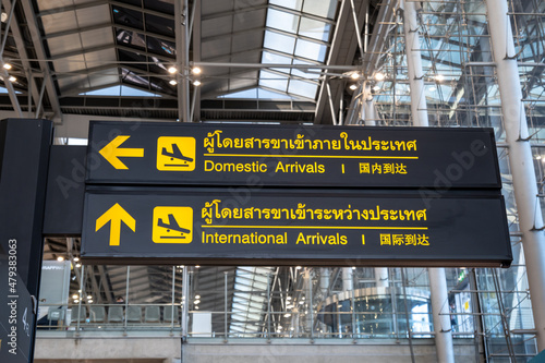 Airport arrival board sign. Flight arrival information board in airport written in English, Chinese and Thai language