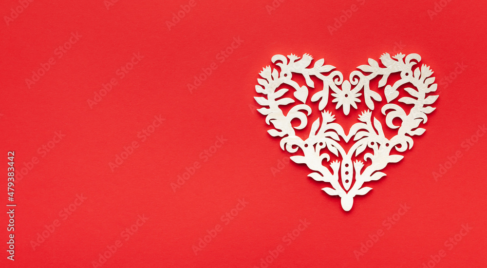 Festive composition with openwork white heart on red background. Top view, copy space. Valentine's day concept.