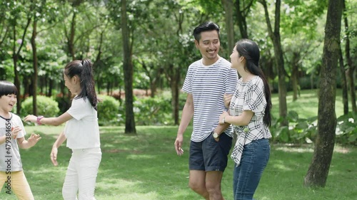 Asian family, parents and kids walking in green park