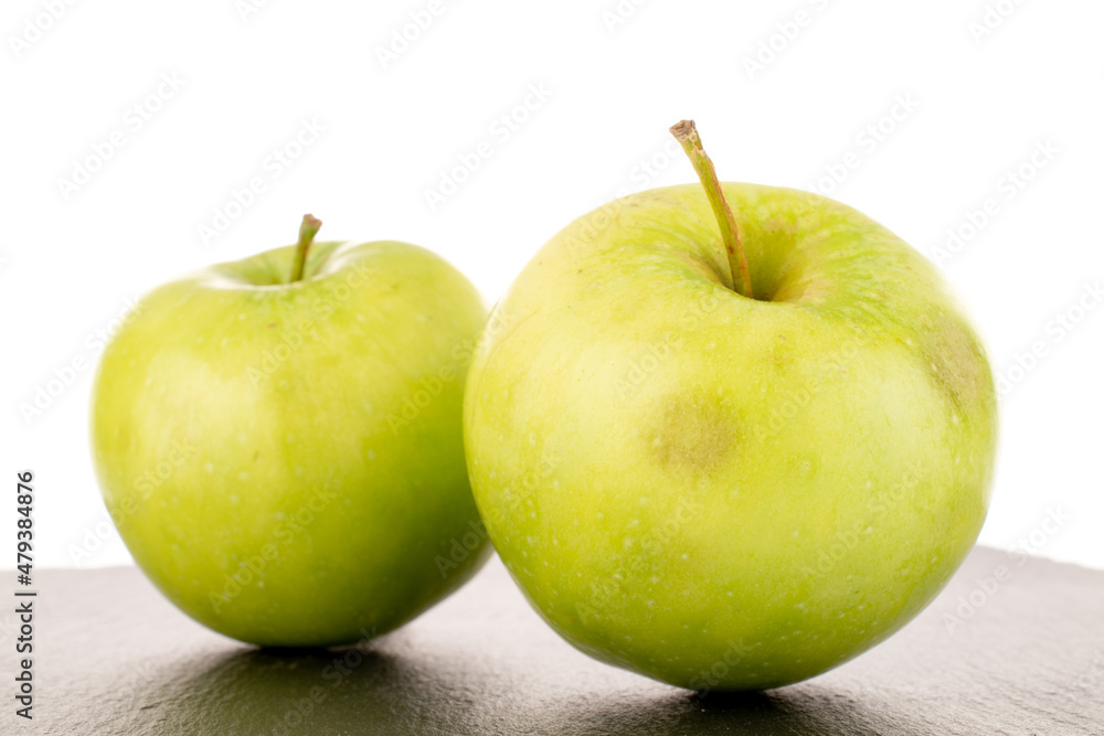 Two sweet green apples on a slate stone, close-up, isolated on white. Two sweet green apples on a slate stone, close-up, isolated on white.