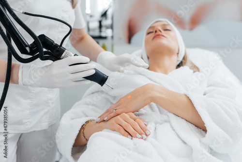 A young girl gets carbon peeling for the skin of her hands in a beauty salon. Laser pulses cleanse the skin. Hardware cosmetology. The process of photothermolysis, warming the skin.