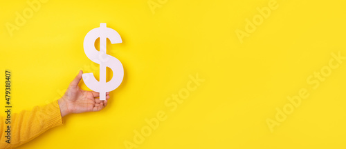 hand holding dollar symbol over yellow background, panoramic layout