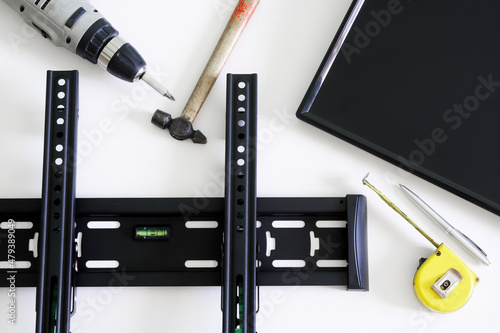 TV wall mount bracket, electric drill, fountain pen, tape measure, hammer and monitor on a white background. The concept of mounting a TV or computer monitor on a wall photo
