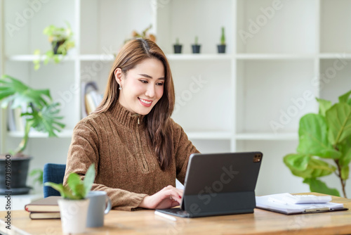 Pretty young Asian female student studying online on laptop computer. © amnaj