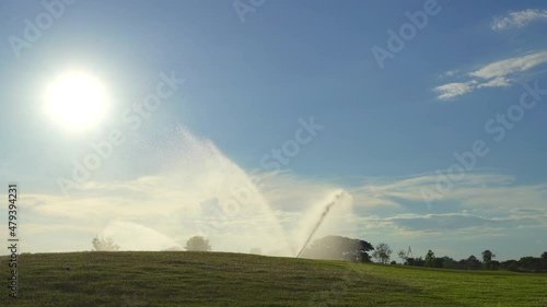 Automatic high-pressure water sprinkler at the golf course watering the grass photo