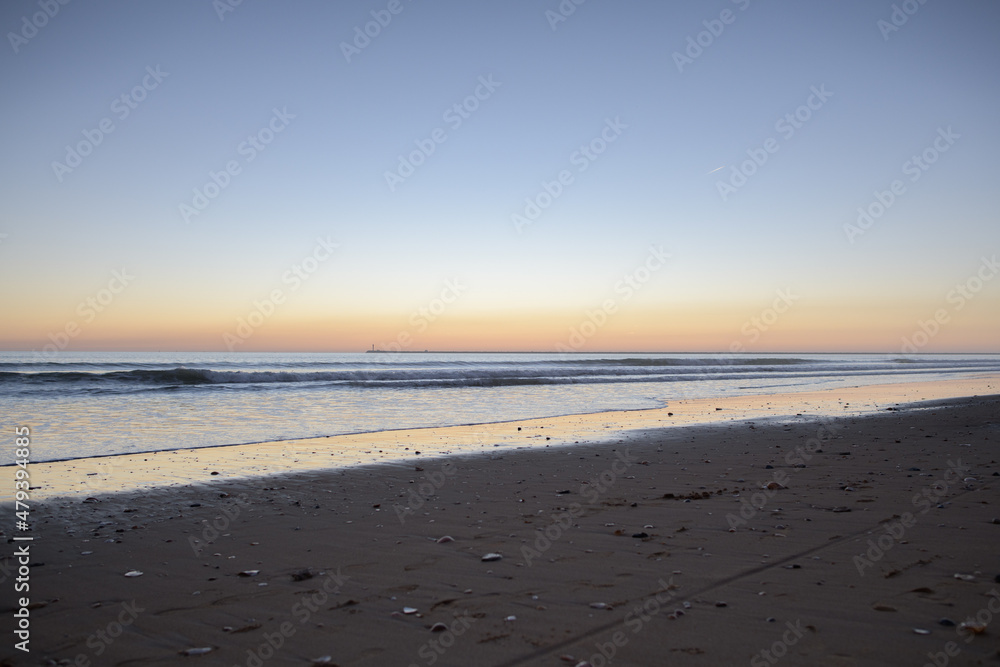 beach and breakwater with small waves at sunset