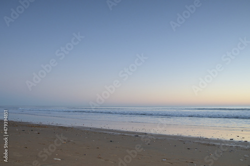 beach and breakwater with small waves at sunset