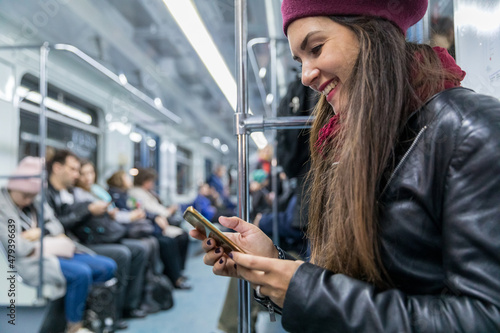 Happy woman using phone travelling by metro in Moscow