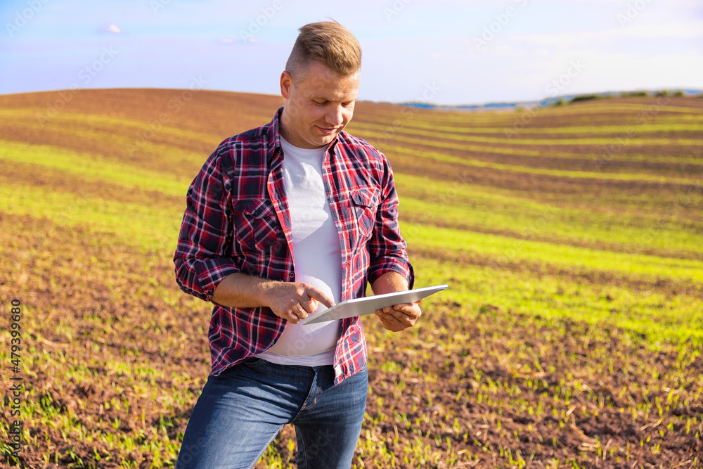 © Kaspars Grinvalds - Farmer standing in field and using digital tablet