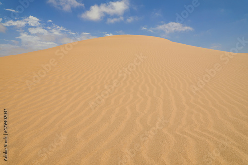 Yellow sand dunes with wavy textures against a blue sky in Swakopmund