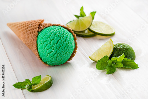 green ice cream with lime and mint in a cone on a white background