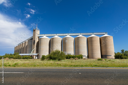 Grain silos in the field with an asphalt road in the foreground 