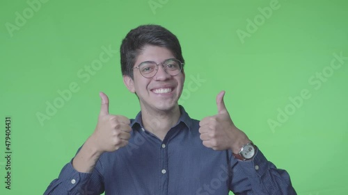 hombre latino diciendo si con la cabeza y pulgares arriba con fondo verde photo