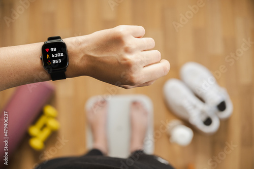Foto Looking at fitness tracker displaying heart rate, steps count and burnt calories while standing on scales, first person view