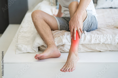 Valokuva Shin pain, man suffering from ache and doing self-massage at home