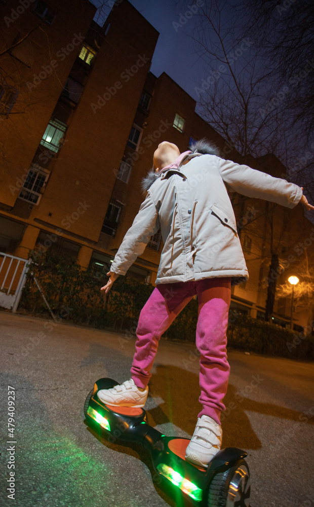 Sport and Mental Health series. Hispanic American girl enjoying her electric scooter on a street in her neighborhood on a night walk in autumn concept: freedom, joy, happiness, urban culture
Sport and Mental Health series. Hispanic American girl enjoying her electric scooter on a street in her neighborhood on a night walk in autumn concept: freedom, joy, happiness, urban culture