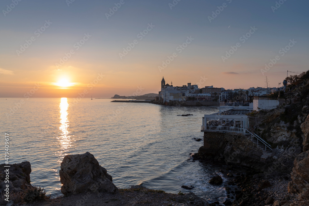Sunset over the sea in Sitges, an old town with a beach, bars and restaurants on the Mediterranean Sea, Catalonia, Spain near Barcelona.