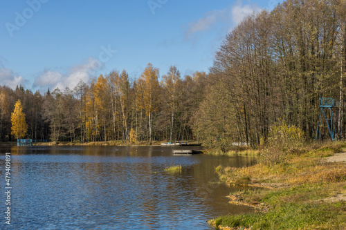 Sunny autumn in the park. Autumn landscape with colorful yellow, orange and red trees and reflection in the pond.