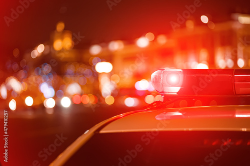 Police car red color emergency light (siren) at the night city lights background.  © Maxim Kukurund