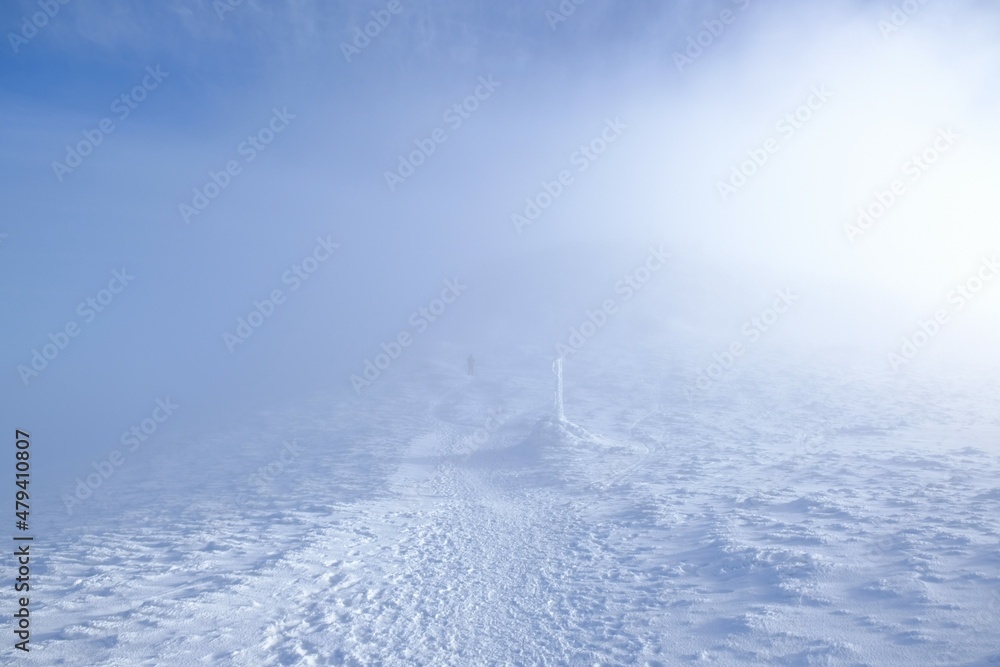 A frozen pole marking trail in the mountains by path on foggy and sunny winter day. Babia Gora peak in background. Diablak, Beskid Zywiecki, Poland A frozen pole marking trail in the mountains by path on foggy and sunny winter day. Babia Gora peak in background. Diablak, Beskid Zywiecki, Poland