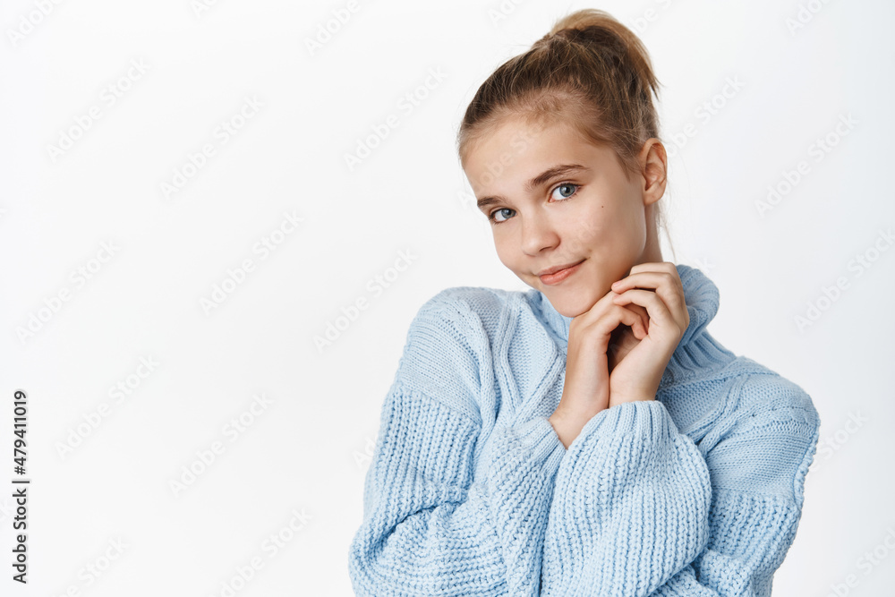 Portrait of beautiful little girl in cute winter sweater, touching her healthy young face and smiling, standing over white background Portrait of beautiful little girl in cute winter sweater, touching her healthy young face and smiling, standing over white background