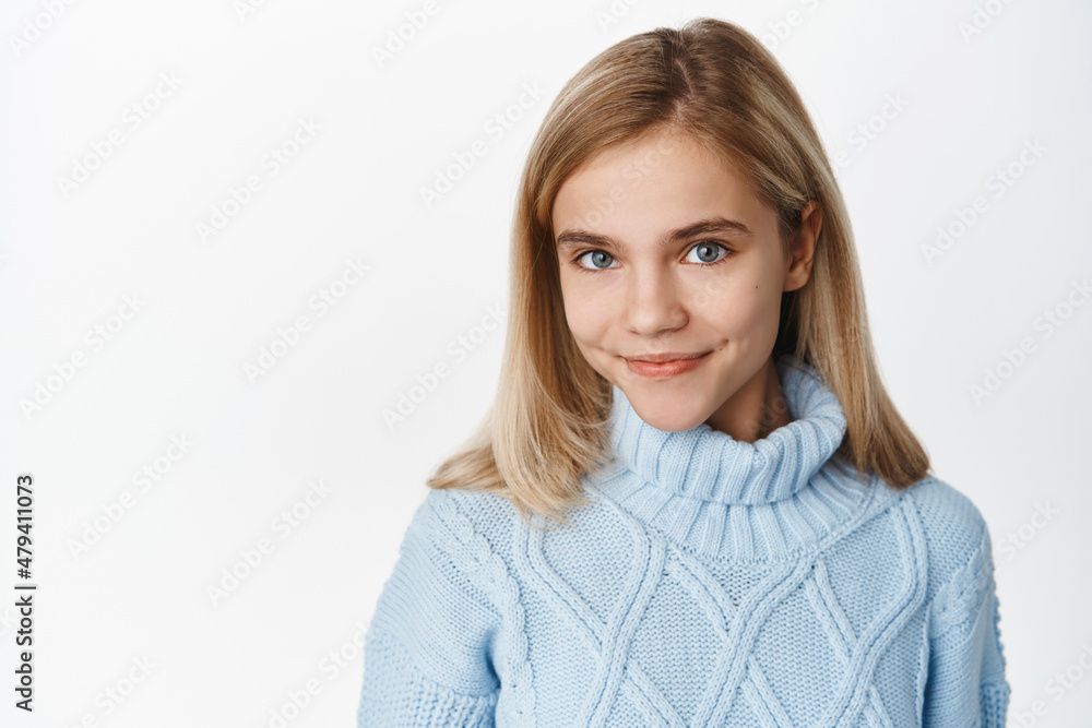 Close up portrait of stylish modern little girl, child in winter sweater posing against white background, smiling cute, standing over white background Close up portrait of stylish modern little girl, child in winter sweater posing against white background, smiling cute, standing over white background