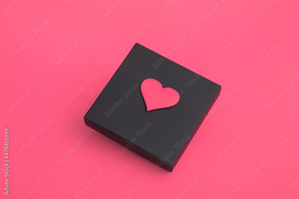 Gift black box with hearts on a pink background. Closeup copy space Gift black box with hearts on a pink background. Closeup copy space