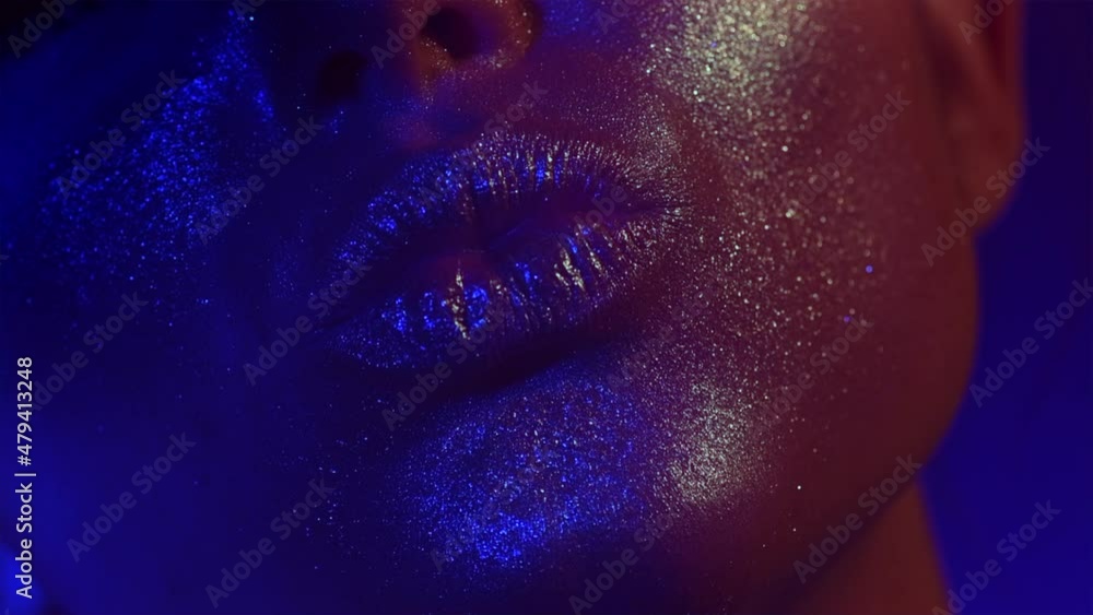 Fashion model golden make up woman kiss lips in bright sparkles, golden and blue colorful lights, beautiful girl lips, mouth. Trendy glowing gold skin make-up. Art design. Glitter metallic shine Fashion model golden make up woman kiss lips in bright sparkles, golden and blue colorful lights, beautiful girl lips, mouth. Trendy glowing gold skin make-up. Art design. Glitter metallic shine