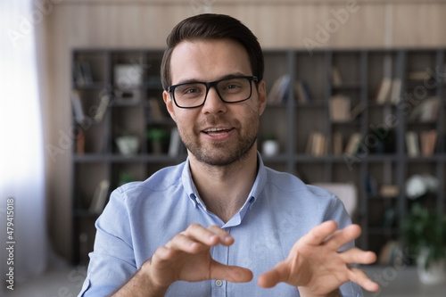 Head shot portrait businessman in glasses speaking, making video call, smiling teacher mentor speaking, leading recording webinar, confident entrepreneur freelancer engaged in virtual conference