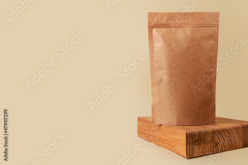 Fototapeta Naklejka Na Ścianę i Meble -  Pouch bag mockup wooden podium neutral beige background monochrome. Merchandise packaging Blank brown kraft paper pack coffee beans product template copy space. Tea food snack delivery Shop store sale