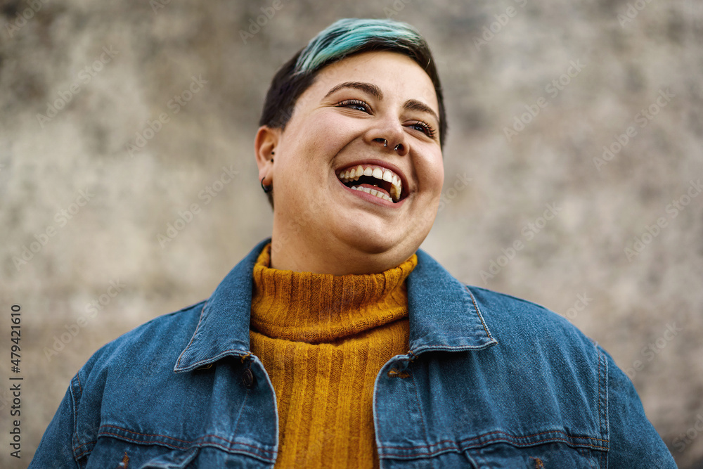 A young woman of non-binary sexuality smiles showing her teeth - obrazy, fototapety, plakaty 