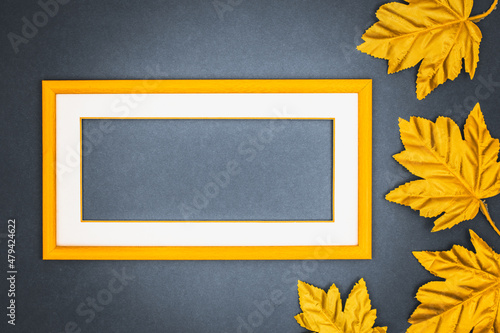 Creative layout, delicate yellow frame with a white passe partout with an empty space for the slogan, Golden leaves, Flat lay, Abstract colors, dark, navy blue background