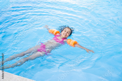 Pretty little girl swimming in outdoor pool and have a fun