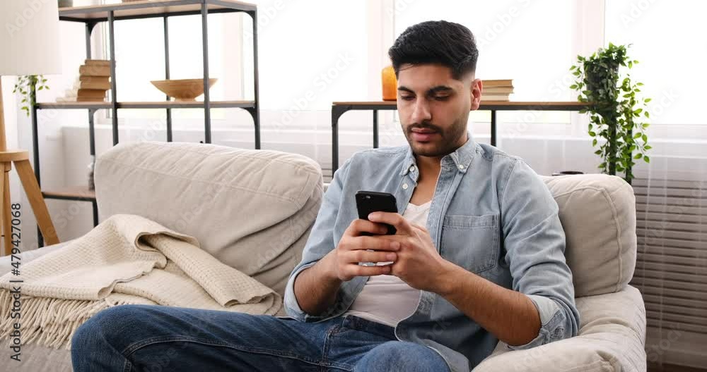 Upset man throwing mobile phone at home Upset man throwing mobile phone at home