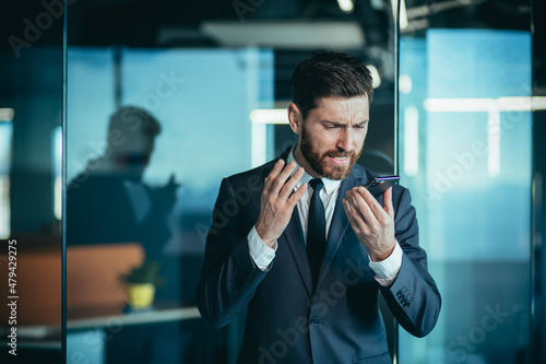 Fotografia Angry and nervous boss shouting into phone, during phone conversation with emplo