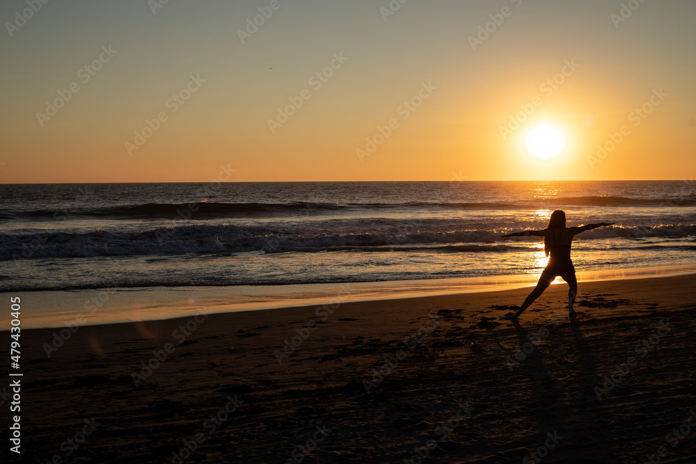 silhouette of woman exercising on the beach at sunset
