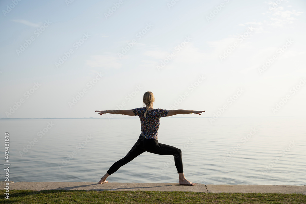 Frau macht Yoga vor Wasser