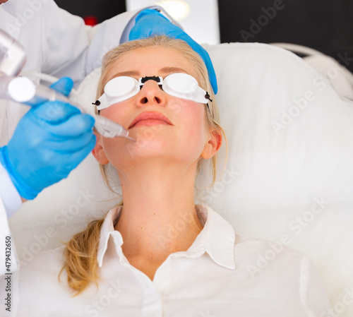 Obraz na plátně Female client receiving hardware laser treatment to resurfacing and tightening facial skin at cosmetology clinic