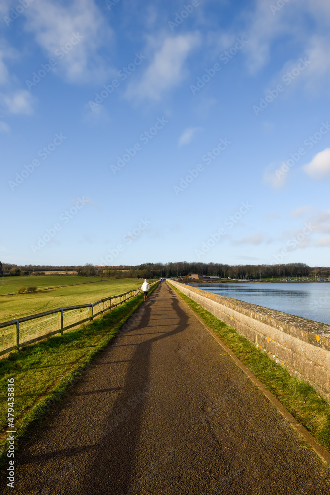 Scenic countryside location by a river with people walking on the footpath in the background