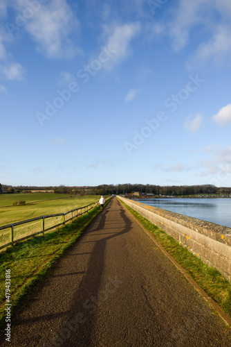 Scenic countryside location by a river with people walking on the footpath in the background